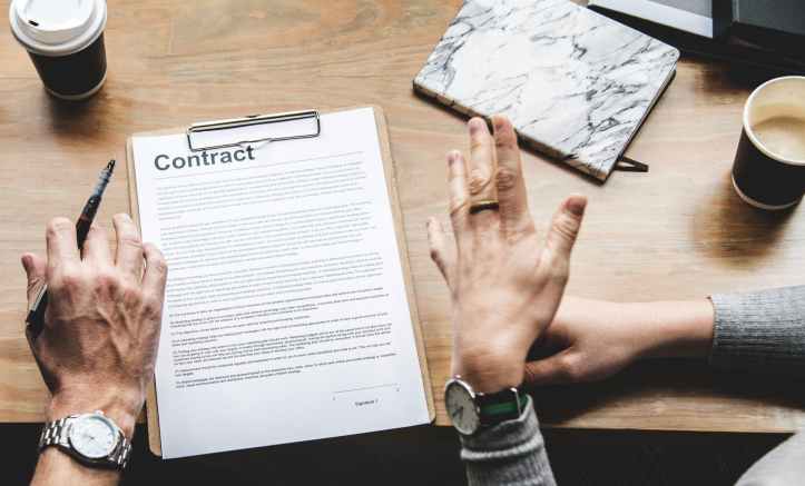 person holding pen in front of contract